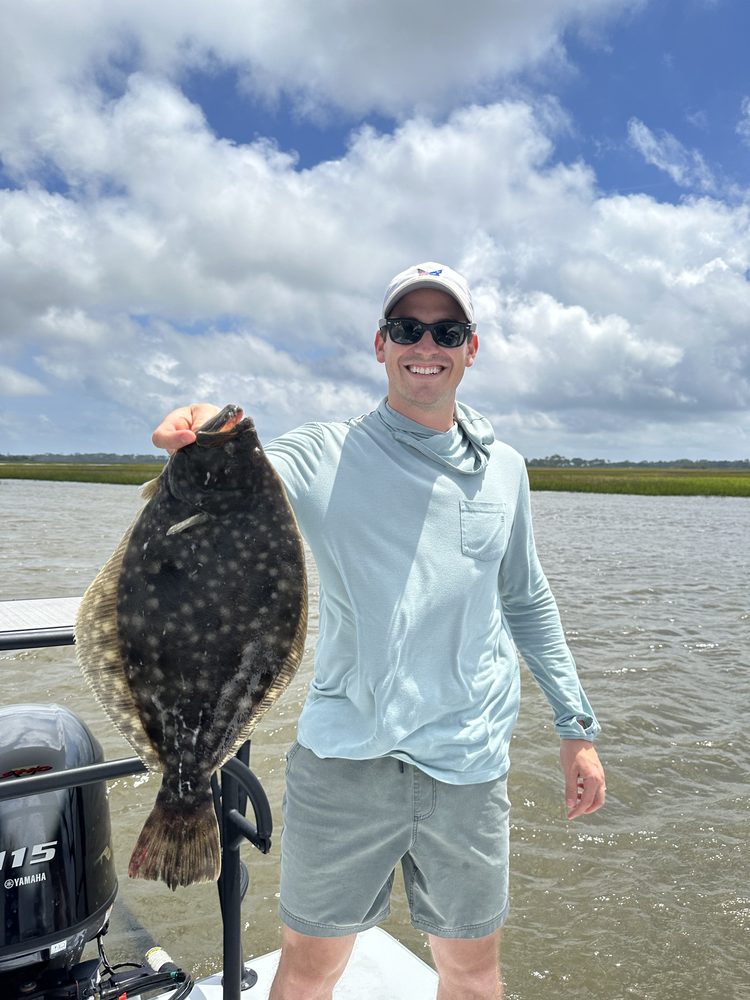 Angler holding a large flounder in the shallows