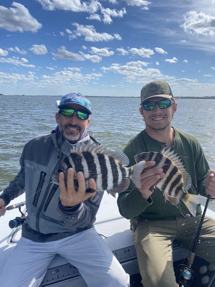 Two anglers on the skiff, each holding a sheepshead