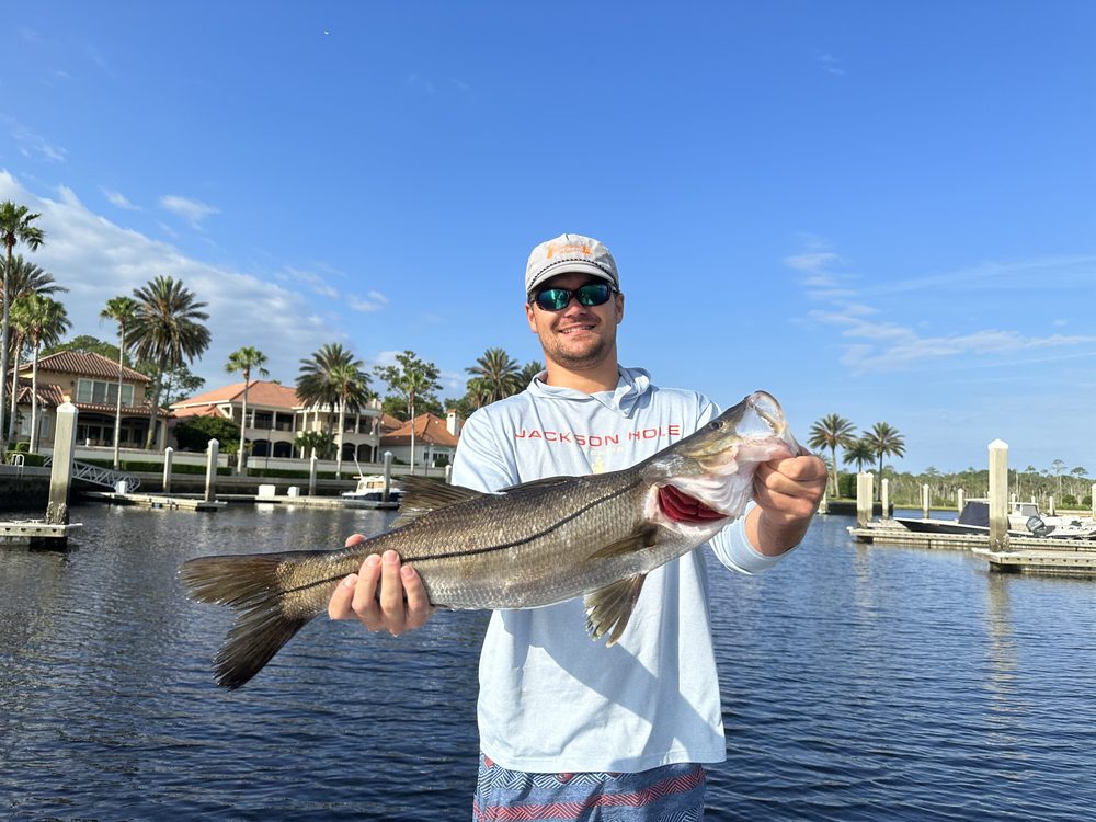 Angler holding a snook on a residential canal