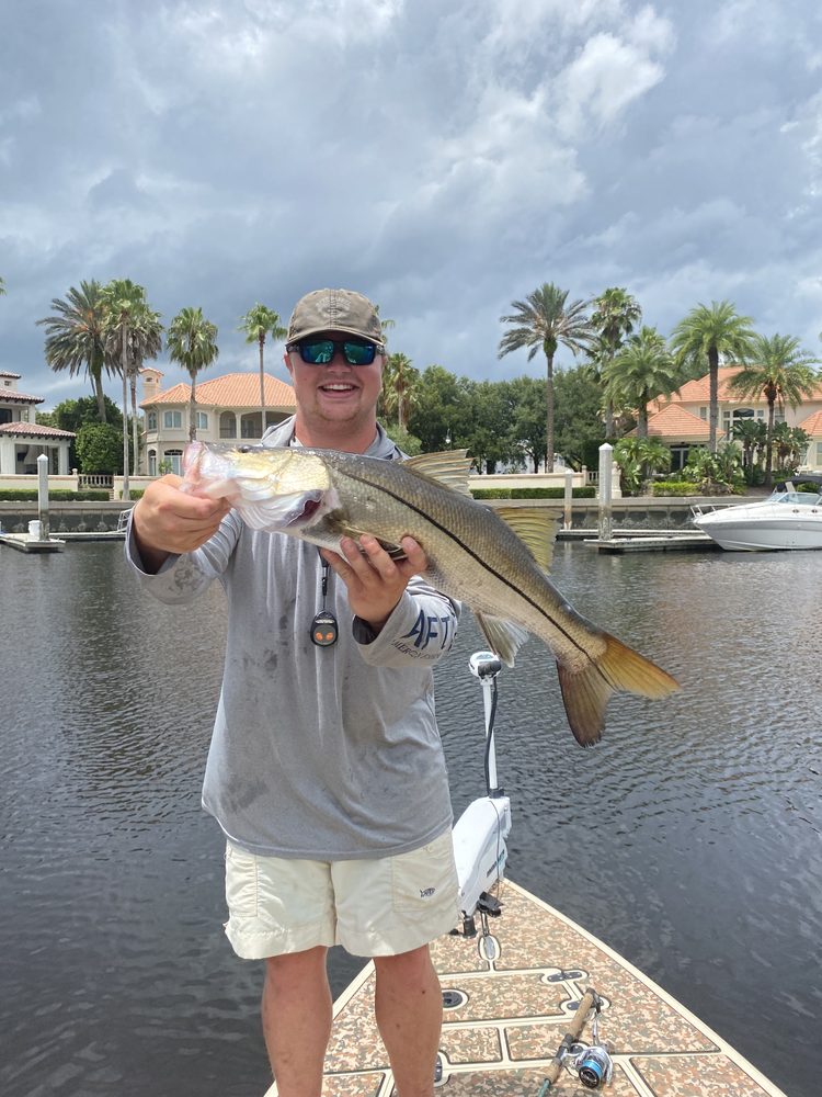 Angler on the skiff holding a snook beside the docks