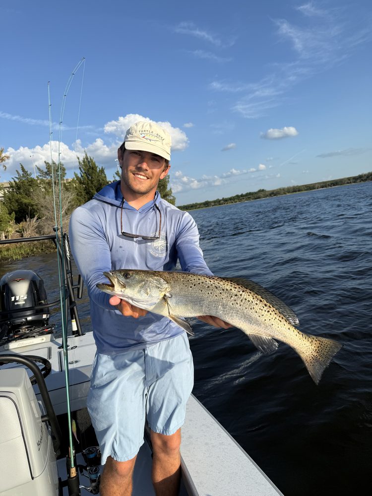 Angler on the skiff holding a spotted seatrout